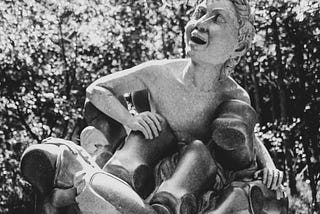 A happy human-like being emerges from a statue of a vice-like robotic grip.