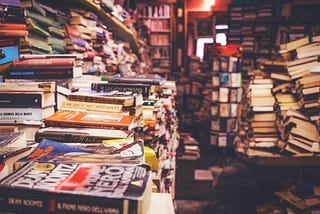 A room full of flat stacked books with a narrow twisty isle down the “center.”