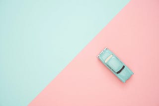 Divide between blue and pink sides of a photo, with a blue toy car on the pink side