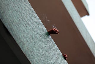 Photo of hands, balcony and cigarette.