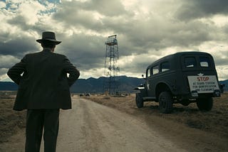 Robert J. Oppenheimer staring at the trinity tower in a wide and open desert called Los Alamos