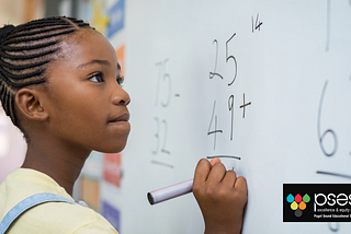 A young black girl works on a math equation on a white board.