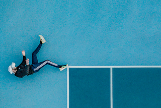 Man lying alone on a tennis court with 3D glasses on