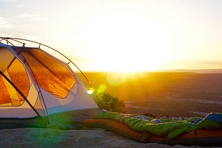 A sunrise across a valley , with a tent in the foreground