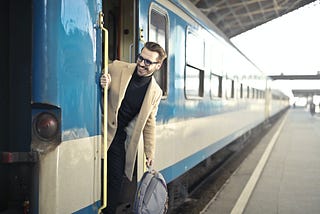 A happy, smiling man arrives at his destination after traveling by train