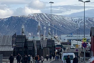 Walk along street leading to Reykjavik Harbor with snow-capped mountains in background.