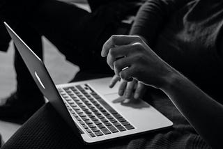 A black and white photo of a person hesitating to type on a laptop. Photo by Sergey Zolkin on Unsplash