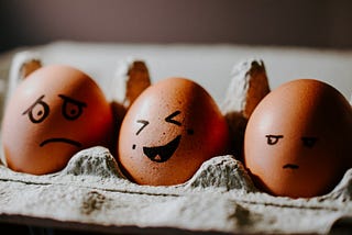 Three chicken eggs showing different feelings