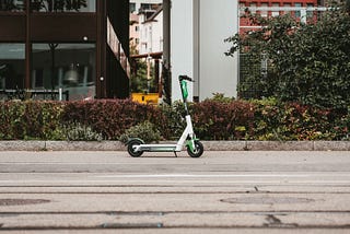A Lime rental e-scooter stands alone on a city street.