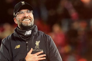 Jurgen Klopp smiling with his hand on his heart.