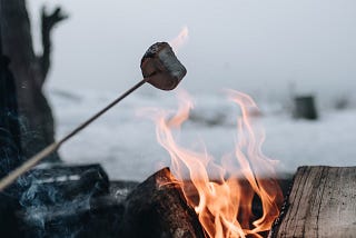 A burnt marshmallow being roasted over a campfire.