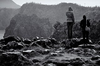 A black and white photo of two women standing on a cliff in Okinawa, Japan.