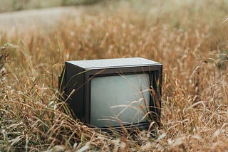 An old television sitting in a field.