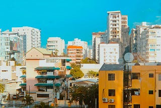 A saturated city-scape of colorful high-rise apartments and other buildings surrounded by power lines and trees in Santo Domingo, Dominican Republic.