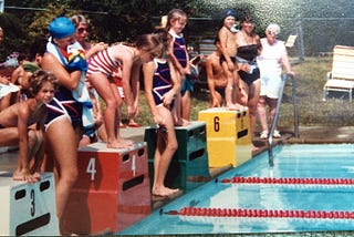 Young children on diving blocks at the start of a swim race