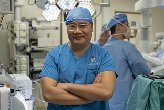 Professor Cheung Tan-To stands in a robotic operating theatreProfessor Cheung Tan-To, dressed in blue scrubs and a blue cap stands in a robotic operating theatre