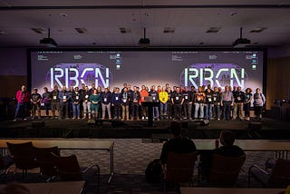 The speakers, workshop organizers and organizing team of the RoboCon 2024 on stage. Behind of this growd of roughly 40 people, there is the screen with RBCN logo.
