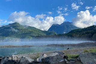A mountain scene with a misty lake in front.