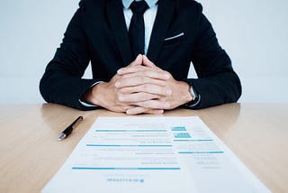 Man sitting at desk with hands intertwined