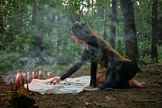 A woman, tarot cards and candles in a wood