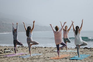 A group of women doing yoga on a beach