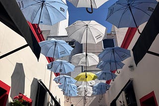 A street with hanging umbrellas in the colors of the Argentinian flag. The photo was taken on the charming streets of San Telmo district in Buenos Aires.