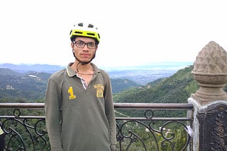 A boy standing in front of railings with hills behind