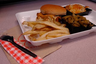 school lunch in a styrofoam tray including a fried chicken sandwich, french fries, and green beans