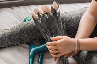 A girl sitting with her crutches and holding pink flowers