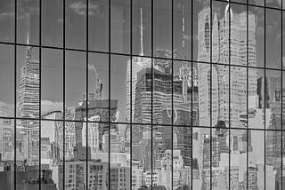 A rectangular grid of the side of a skyscraper in New York City reflects a distorted view of Manhattan. The grid appears undistorted.