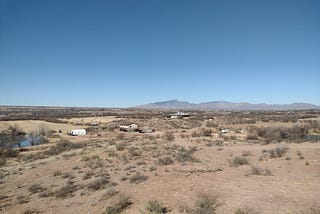 Landscape of rural Arizona desert with a ranch and a pond.