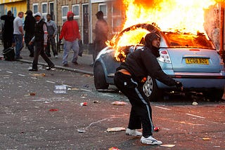 London Riots of 2011. Man in front of blazing car throws something