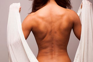 Woman, naked back, holding fabric over shoulders