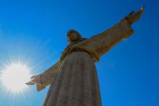 stone statue of a robed figure, arms spread out to the sides. looks Christian.