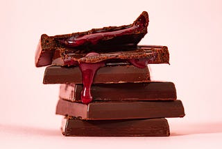 A stack of thin chocolate squares filled with raspberry jam.