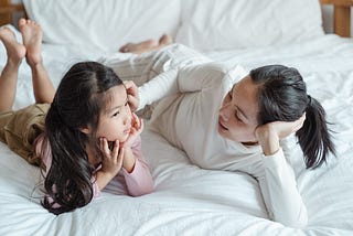 Mother lovingly talking to her daughter on a bed.