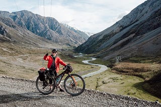 Robbie gives a thumbs up with a bikepacking bike in an alpine landscape