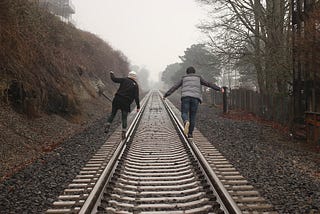 A couple balancing on railroad tracks
