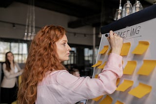 Woman Writing on a Whiteboard with Sticky Notes