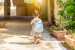 little girl walking into first day of kindergarten