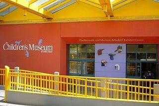 outside of Seattle Children’s Museum building with logo visible on red wall