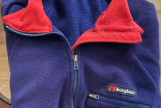 Blue quarter zip front fleece jacket with red collar and a zippered left breast pocket.