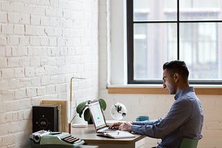 Man Sitting on Green Chair While Using Laptop to work