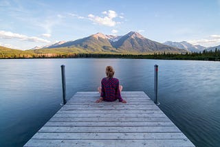 Person staring out into a river and mountains