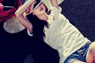 A girl is sleeping with her head on a skateboard.