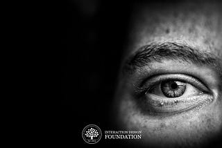 Black and White photograph of a person’s eye, with a small logo of the Interaction Design Foundation at the bottom.