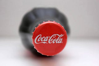 A bottle of coca-cola laid out horizontally on a surface