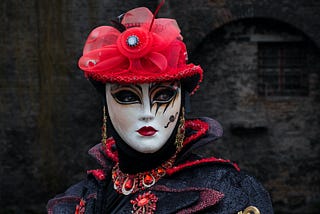 A woman wearing an elaborate and colourful theatrical mask and costume.