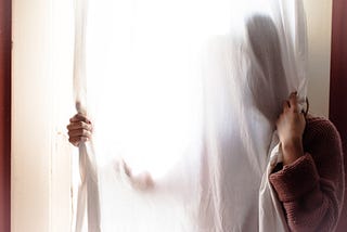 Woman hidden behind a curtain