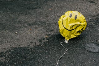 Deflated yellow balloon with smiley face